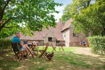 Historisch gebouw met een erf ervoor waar mensen op een terras zitten