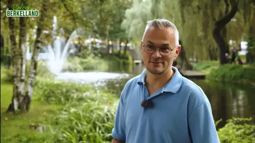 meneer bij het water met een fontein en bomen