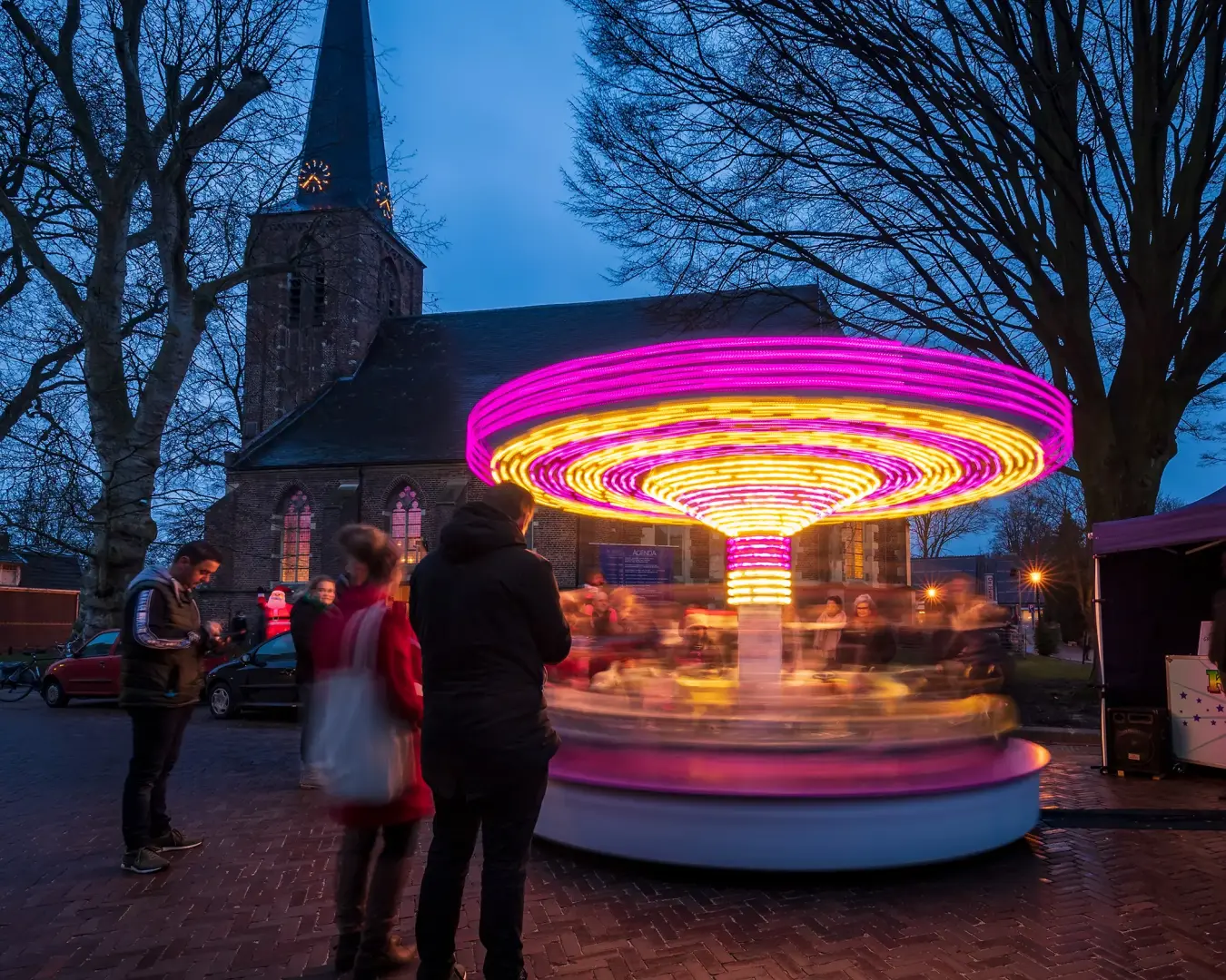 Draaimolen in het donker bij een kerk