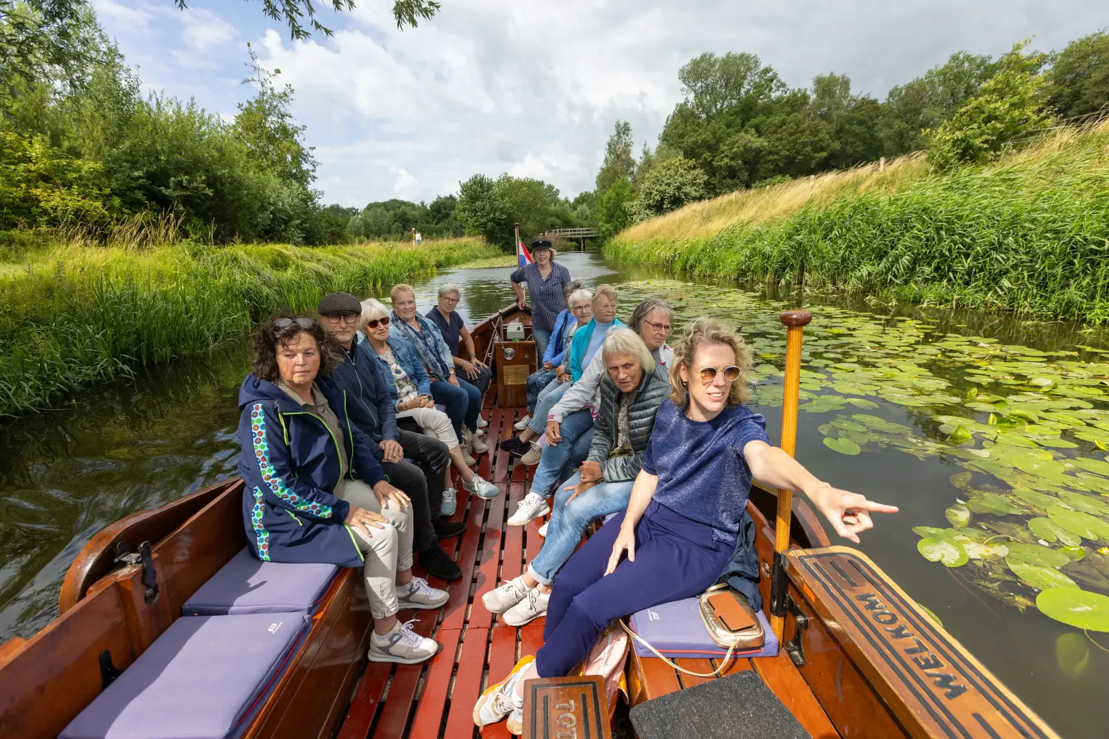 groepje mensen op een platte houten boot in een klein riviertje