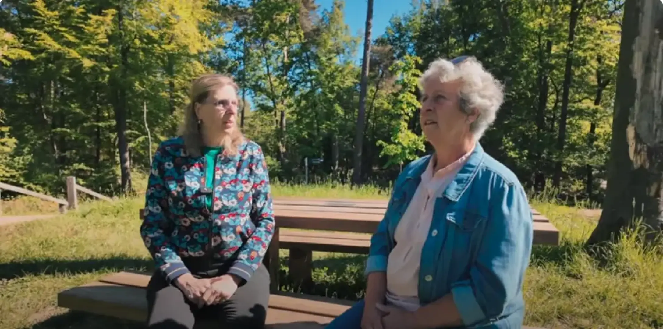 Twee mevrouwen op een picknickbankje in een bos