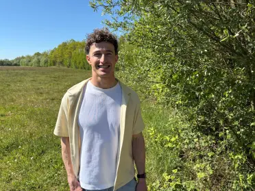 Weerman Jordi Huirne voor een veld met een struikenrand