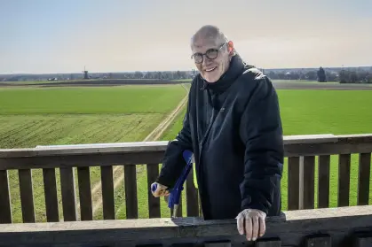 meneer met krukken in ene open houten toren met rondom weilanden
