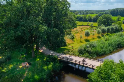 Brug bij bomen en weilanden met een fietser in de zomer